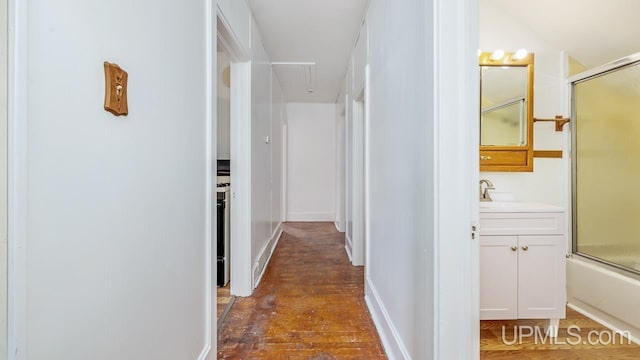 corridor with dark hardwood / wood-style flooring and sink