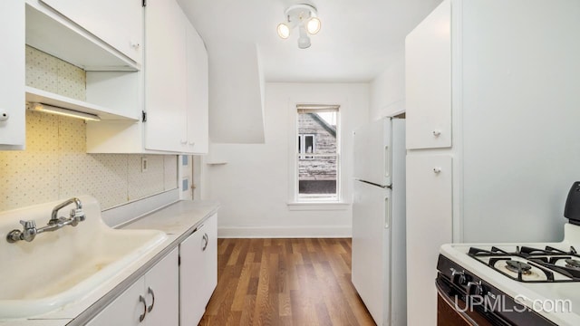 kitchen featuring white cabinetry, sink, tasteful backsplash, dark hardwood / wood-style floors, and white appliances