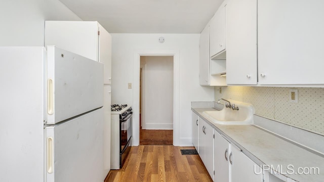 kitchen featuring range with gas cooktop, sink, light hardwood / wood-style flooring, white cabinets, and white fridge