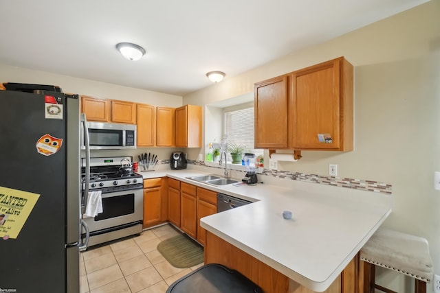 kitchen with sink, kitchen peninsula, a breakfast bar area, light tile patterned floors, and appliances with stainless steel finishes