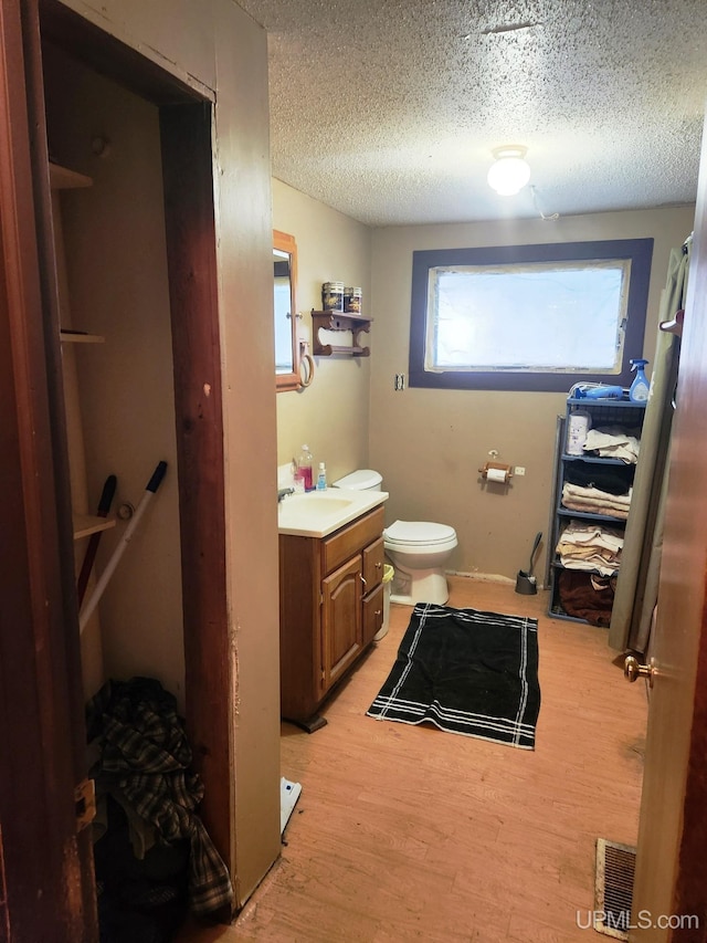 bathroom with wood-type flooring, vanity, a textured ceiling, and toilet