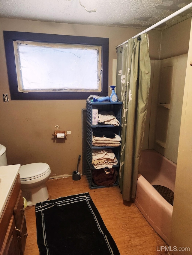 full bathroom with wood-type flooring, vanity, a textured ceiling, and shower / bathtub combination with curtain