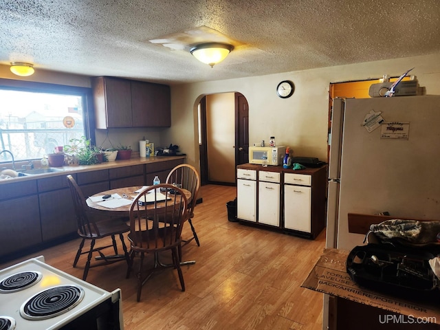 kitchen with a textured ceiling, light hardwood / wood-style floors, white appliances, and sink