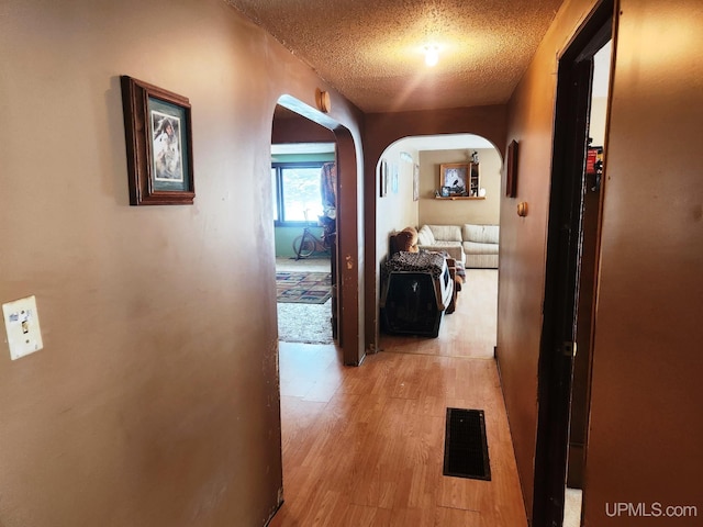 hall featuring a textured ceiling and light hardwood / wood-style flooring