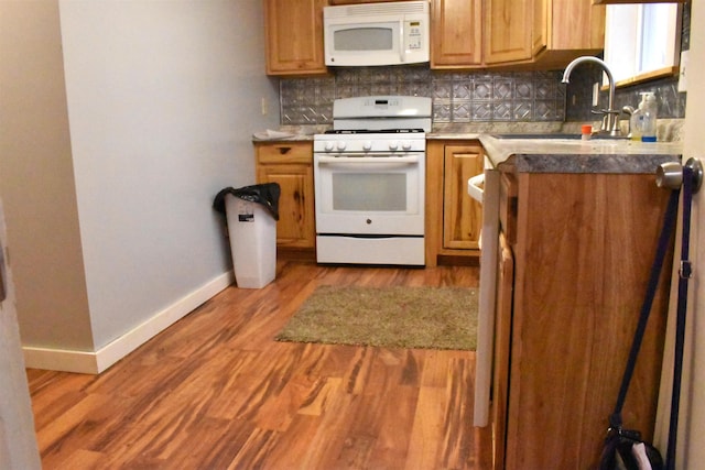 kitchen featuring backsplash, wood-type flooring, white appliances, and sink