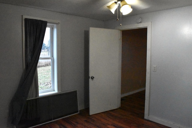 unfurnished bedroom with ceiling fan and dark wood-type flooring