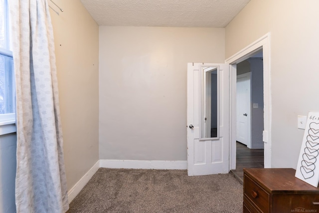 interior space featuring dark colored carpet and a textured ceiling