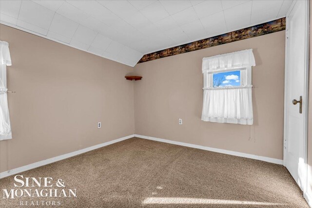 carpeted empty room featuring vaulted ceiling