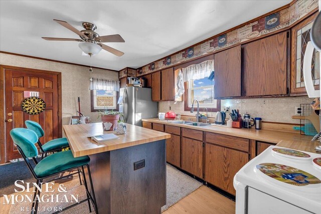 kitchen with stainless steel fridge with ice dispenser, plenty of natural light, sink, and light wood-type flooring