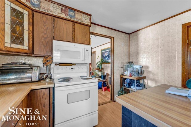 kitchen with tasteful backsplash, white appliances, crown molding, and light hardwood / wood-style flooring