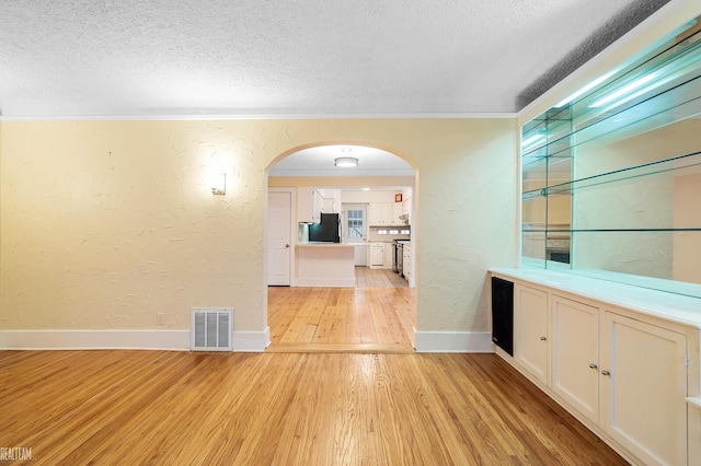 interior space with a textured ceiling, light wood-type flooring, white cabinetry, and refrigerator