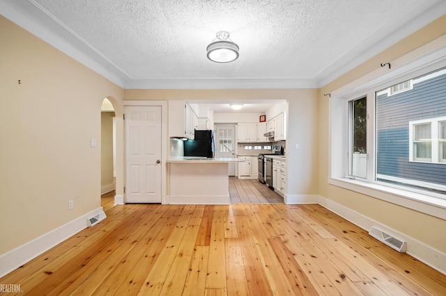 unfurnished living room featuring a textured ceiling, light hardwood / wood-style floors, and a wealth of natural light