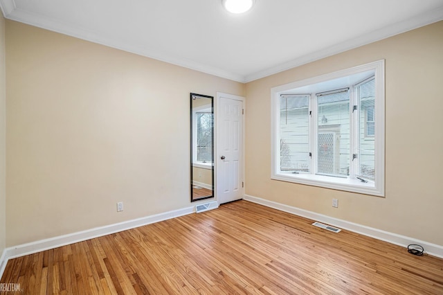 empty room featuring light hardwood / wood-style flooring and crown molding