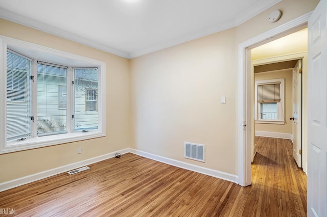 empty room with wood-type flooring, a wealth of natural light, and crown molding