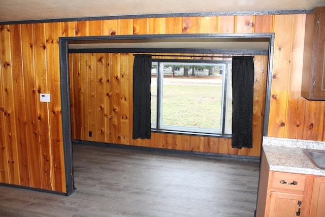 empty room with a textured ceiling, wood walls, crown molding, and dark hardwood / wood-style floors