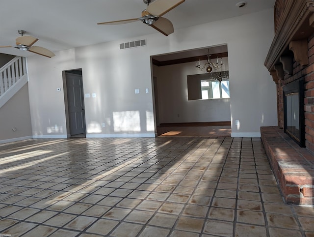 unfurnished living room with tile patterned flooring, ceiling fan with notable chandelier, and a brick fireplace