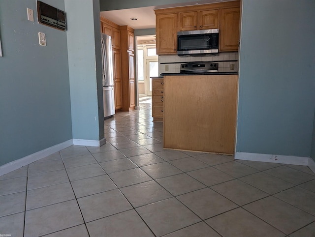 kitchen with light tile patterned flooring, backsplash, and appliances with stainless steel finishes