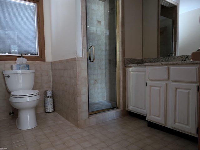 bathroom with tile patterned floors, vanity, tile walls, toilet, and a shower with shower door