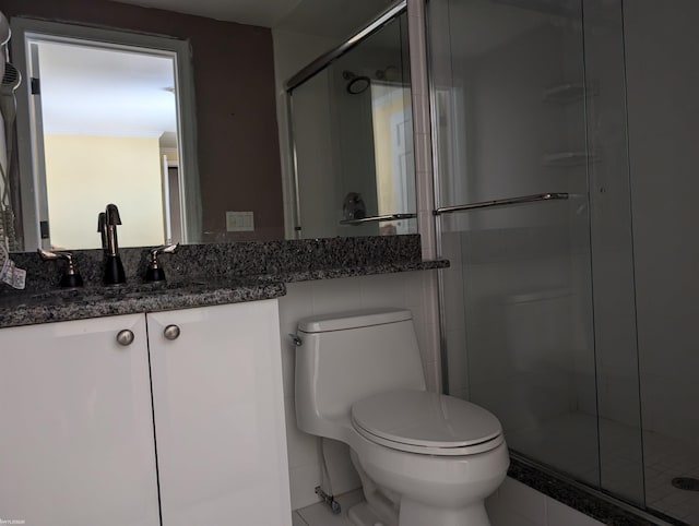 bathroom featuring vanity, an enclosed shower, and toilet