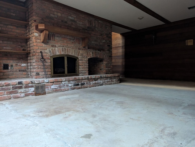 unfurnished living room with beam ceiling, a fireplace, and concrete floors