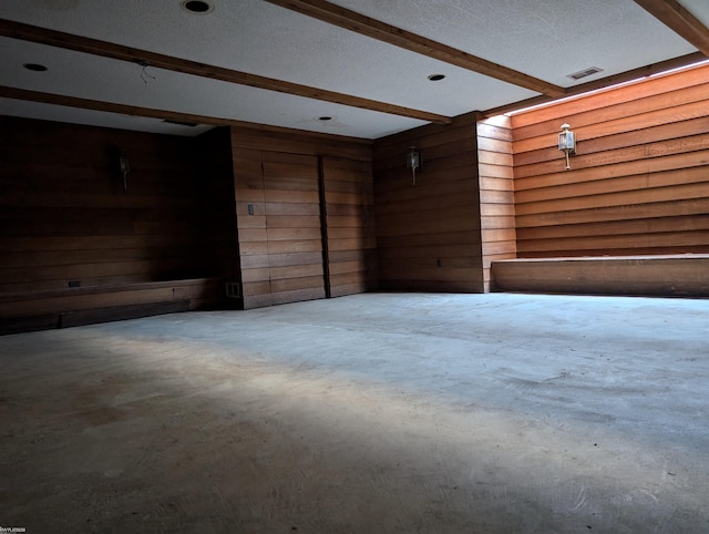 spare room featuring beam ceiling, wood walls, and concrete flooring