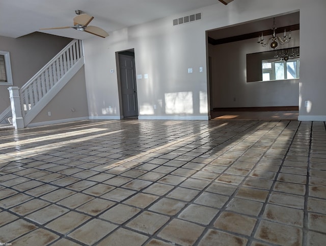 unfurnished living room featuring ceiling fan with notable chandelier