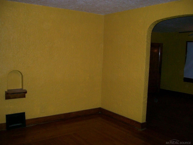 unfurnished room featuring dark hardwood / wood-style flooring and a textured ceiling