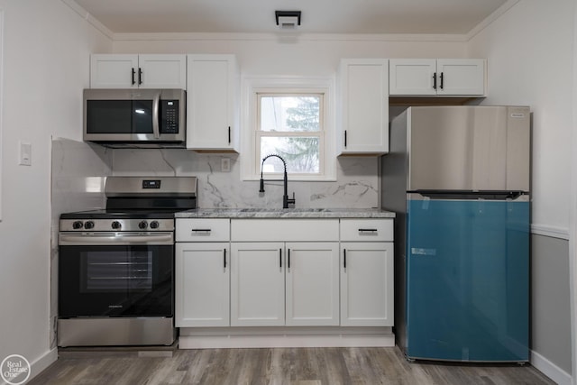 kitchen featuring sink, tasteful backsplash, light stone counters, white cabinetry, and stainless steel appliances