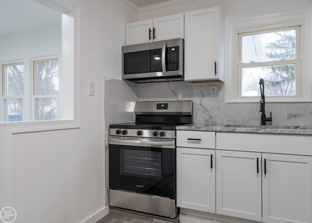 kitchen with tasteful backsplash, white cabinetry, stainless steel appliances, and light stone counters