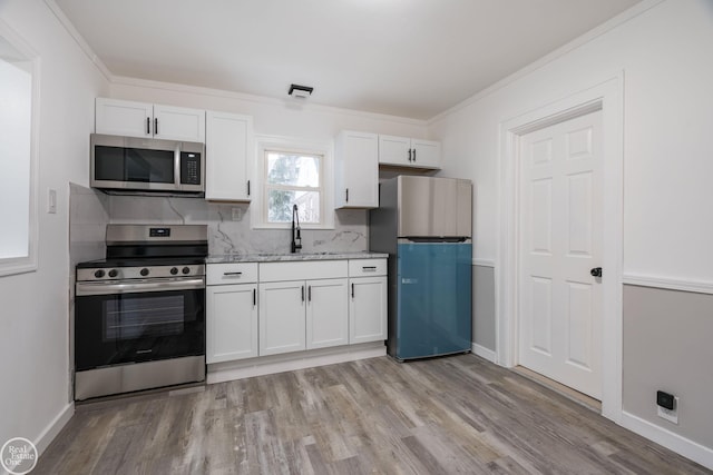 kitchen featuring white cabinets, sink, decorative backsplash, appliances with stainless steel finishes, and light hardwood / wood-style floors