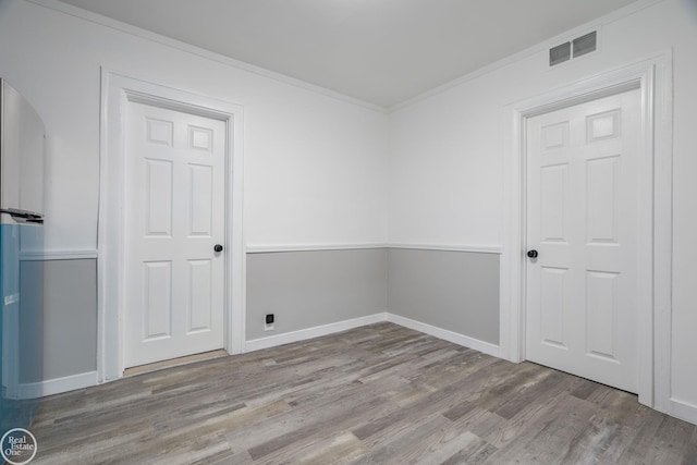 spare room with light wood-type flooring and crown molding