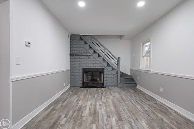 unfurnished living room featuring a fireplace, light wood-type flooring, and ornamental molding