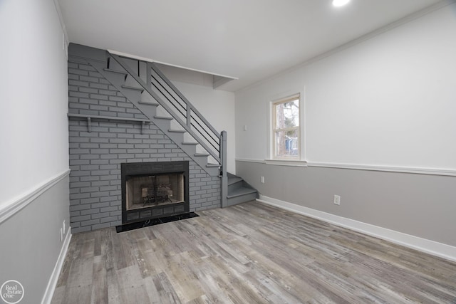 unfurnished living room featuring light hardwood / wood-style floors, ornamental molding, and a fireplace