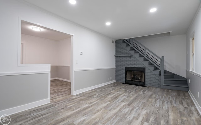 unfurnished living room featuring crown molding, a fireplace, and light wood-type flooring