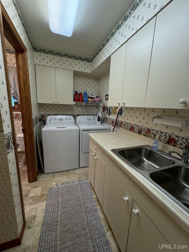 laundry area with washing machine and clothes dryer, sink, and cabinets