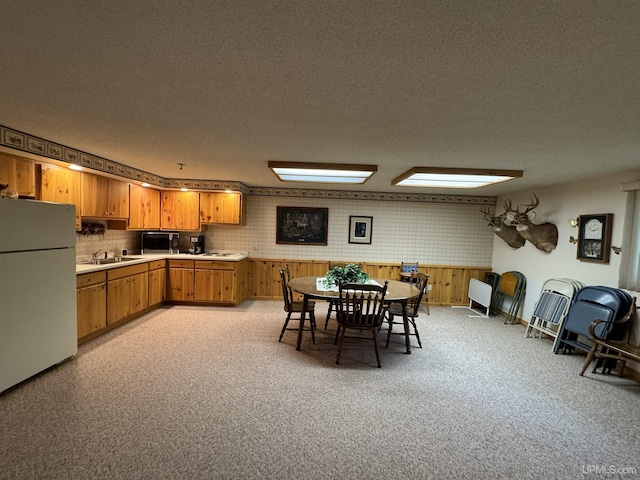 kitchen featuring wood walls, sink, white fridge, and a textured ceiling