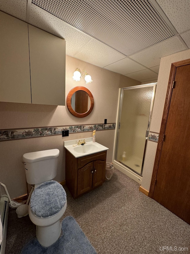 bathroom with a shower with door, vanity, a drop ceiling, and toilet