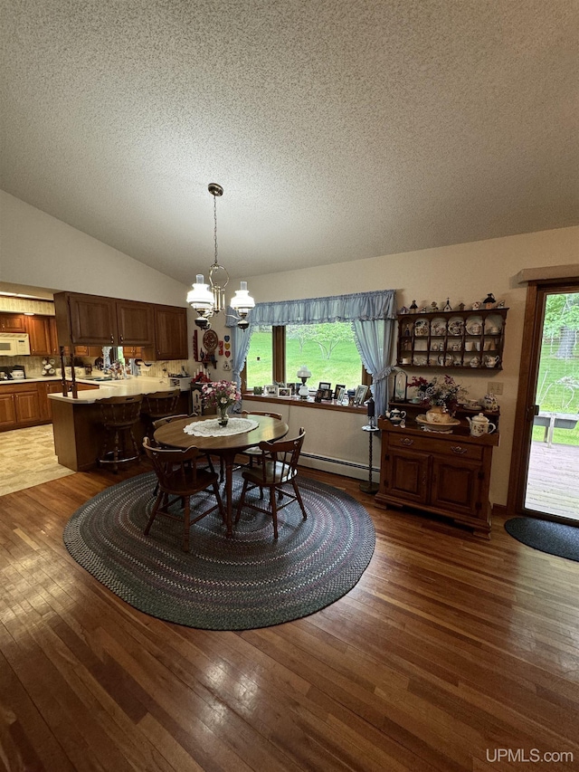 dining area featuring dark hardwood / wood-style floors, a textured ceiling, a chandelier, and vaulted ceiling