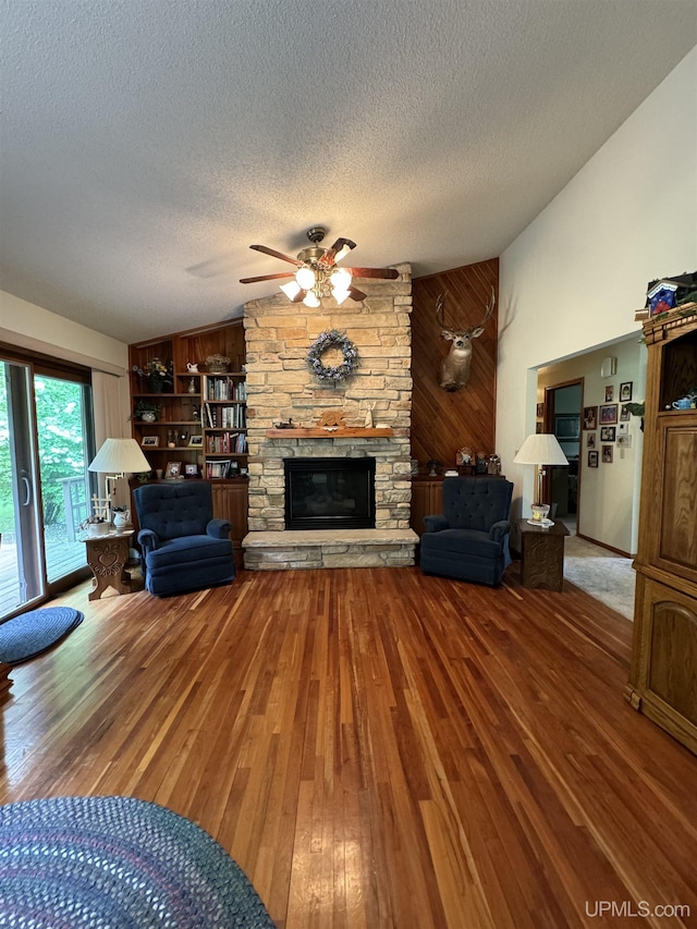 living room with a fireplace, a textured ceiling, hardwood / wood-style flooring, and wooden walls