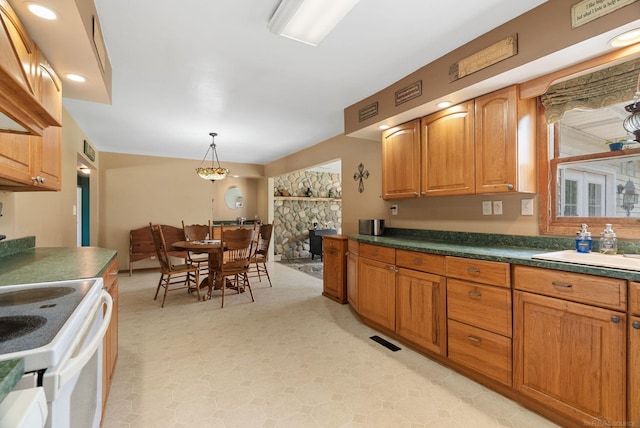 kitchen featuring sink, a fireplace, decorative light fixtures, and white electric stove