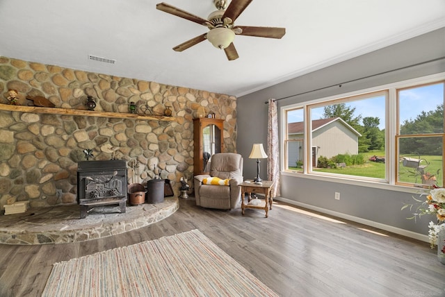 unfurnished room with hardwood / wood-style floors, ceiling fan, and a wood stove