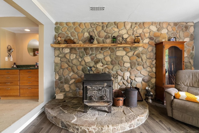 details with a wood stove, crown molding, and hardwood / wood-style flooring