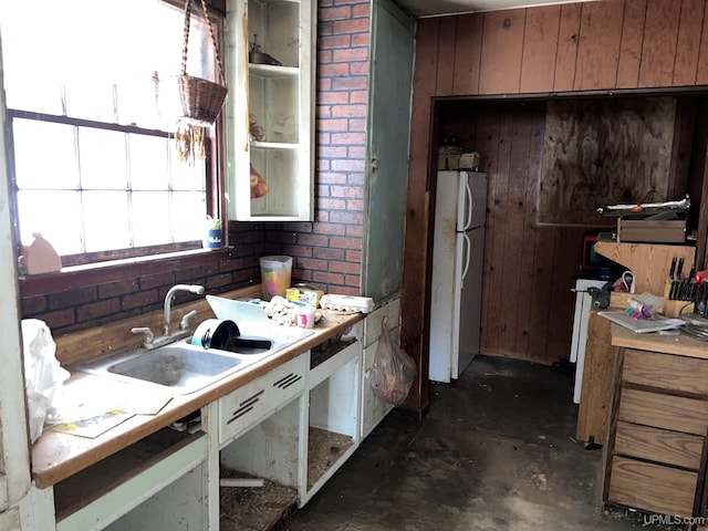 kitchen with wood walls, sink, and white refrigerator