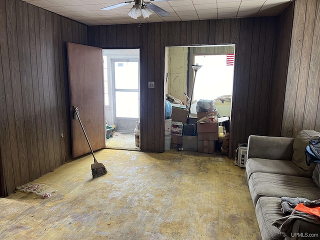 living room featuring ceiling fan and wooden walls