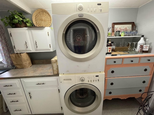 clothes washing area featuring stacked washer / dryer and cabinets