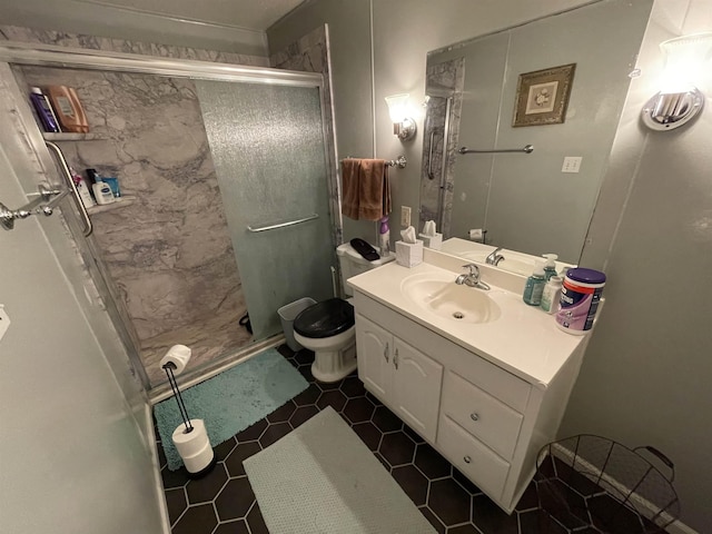 bathroom featuring tile patterned floors, vanity, a shower with shower door, and toilet