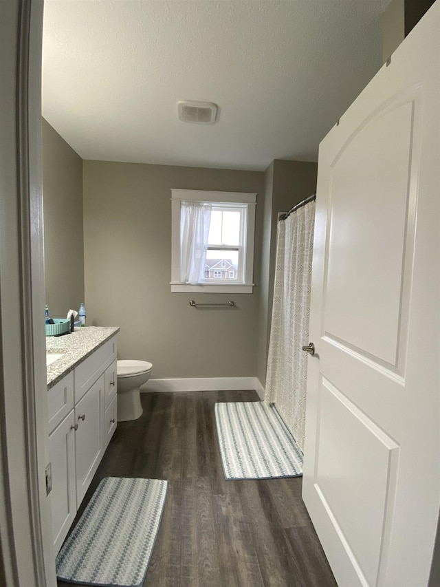 bathroom with vanity, wood-type flooring, a textured ceiling, and toilet