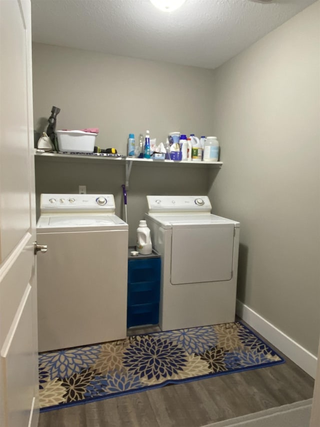 clothes washing area with washing machine and dryer, hardwood / wood-style floors, and a textured ceiling