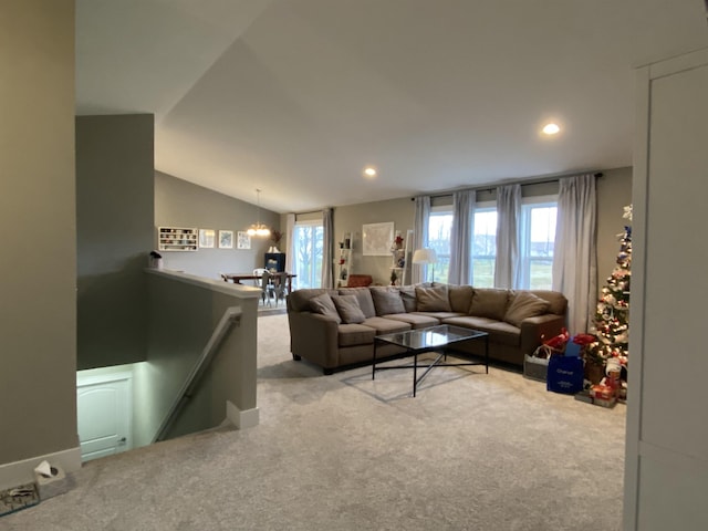 carpeted living room featuring lofted ceiling and a notable chandelier