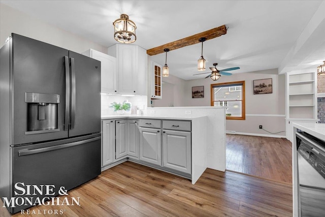 kitchen featuring appliances with stainless steel finishes, light wood-type flooring, ceiling fan with notable chandelier, beamed ceiling, and white cabinets